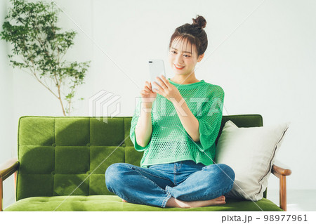 ソファに座ってスマホを見る女性 ソファに座ってスマホを見る女性 98977961
