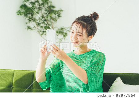 ソファに座ってスマホを見る女性 ソファに座ってスマホを見る女性 98977964