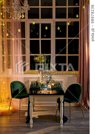 Romantic dinner table setting with festive lights Romantic dinner table setting with festive lights 98978236