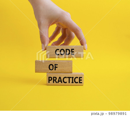 Code of Practice symbol. Concept word Code of Practice on wooden blocks. Businessman hand. Beautiful yellow background. Business and Code of Practice concept. Copy space 98979891
