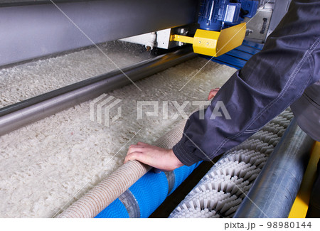 Laundry worker in process of working on automatic machine for carpet washing in dry cleaning 98980144