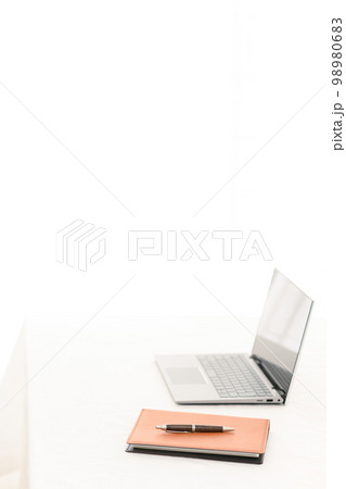 白いテーブルの上にノートパソコンとシステム手帳とペン（ペンピント）のあるシーン 98980683