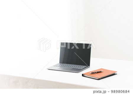 白いテーブルの上にノートパソコンとシステム手帳とペン（ペンピント）のあるシーン 98980684
