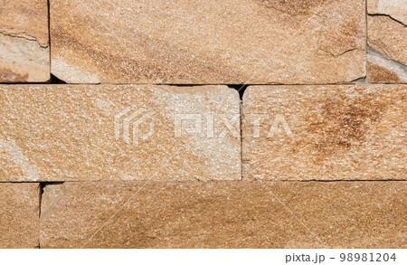 texture of the stone. The yellow stone is carved with brick-shaped plates in bright sunlight. Sunny day 98981204