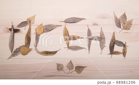 The word autumn from fallen autumn leaves in Russian. The word is collected from autumn leaves on a textured wooden table surface. 98981206