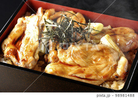 タレがたっぷりかかった熱々の炭火焼き鳥重を黒背景で撮影 タレがたっぷりかかった熱々の炭火焼き鳥重を黒背景で撮影 98981488