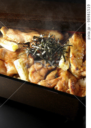 タレがたっぷりかかった熱々の炭火焼き鳥重を黒背景で撮影 タレがたっぷりかかった熱々の炭火焼き鳥重を黒背景で撮影 98981519