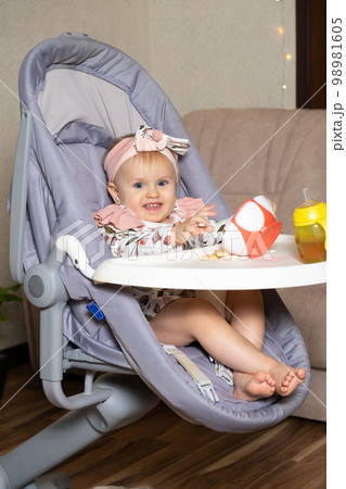A cute one-year-old girl pours cookies out of a plate. Complementary foods for children, self-feeding, sugar in food. 98981605