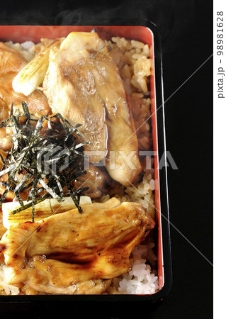 タレがたっぷりかかった熱々の炭火焼き鳥重を黒背景で俯瞰撮影 タレがたっぷりかかった熱々の炭火焼き鳥重を黒背景で俯瞰撮影 98981628