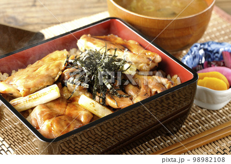 タレがたっぷりかかった熱々の炭火焼き鳥重と味噌汁とお漬物 98982108