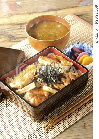 タレがたっぷりかかった熱々の炭火焼き鳥重と味噌汁とお漬物 タレがたっぷりかかった熱々の炭火焼き鳥重と味噌汁とお漬物 98982109