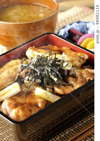 タレがたっぷりかかった熱々の炭火焼き鳥重と味噌汁とお漬物 98982110