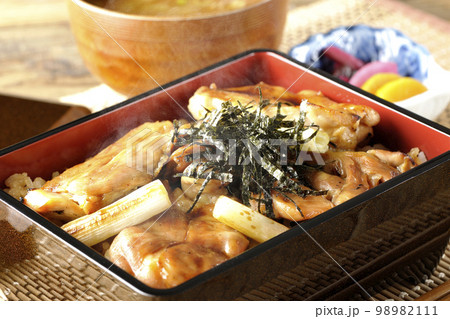 タレがたっぷりかかった熱々の炭火焼き鳥重と味噌汁とお漬物 98982111