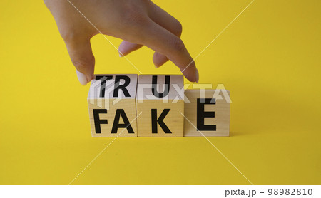 True vs Fake symbol. Businessman Hand turns cubes and changes word Fake to True. Beautiful yellow background. Business and True vs Fake concept. Copy space True vs Fake symbol. Businessman Hand turns cubes and changes word Fake to True. Beautiful yellow background. Business and True vs Fake concept. Copy space 98982810