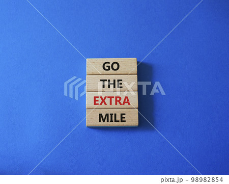 Go the extra mile symbol. Wooden blocks with words Go the extra mile. Beautiful blue background. Business and Go the extra mile concept. Copy space. 98982854