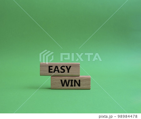 Easy win symbol. Wooden blocks with words 'Easy win'. Beautiful green background. Business and 'Easy win' concept. Copy space. 98984478