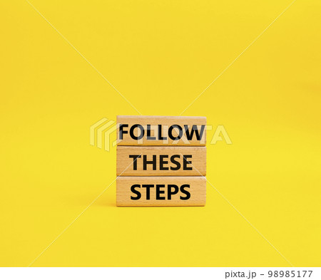 Follow these steps symbol. Wooden blocks with words Follow these steps. Beautiful yellow background. Business and Follow these steps concept. Copy space. 98985177
