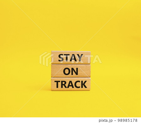 Stay on track symbol. Wooden blocks with words 'Stay on track'. Beautiful yellow background. Business and 'Stay on track' concept. Copy space. 98985178