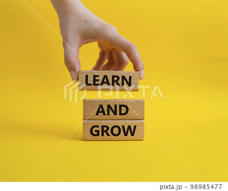 Learn and grow symbol. Concept words 'Learn and grow' on wooden blocks. Beautiful yellow background. Businessman hand. Business and Learn and grow concept. Copy space. 98985477