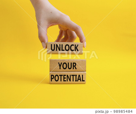 Unlock your Potential symbol. Wooden blocks with words Unlock your Potential. Beautiful yellow background. Businessman hand. Business and Unlock your Potential concept. Copy space. 98985484