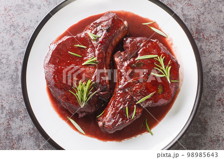 Delicious drunken pork chops fried and then cooked with red wine, herbs and spices close-up on a plate. Horizontal top view 98985643