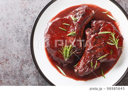 Drunken Pork Chops with red wine sauce and herbs closeup on the plate. Horizontal top view 98985645
