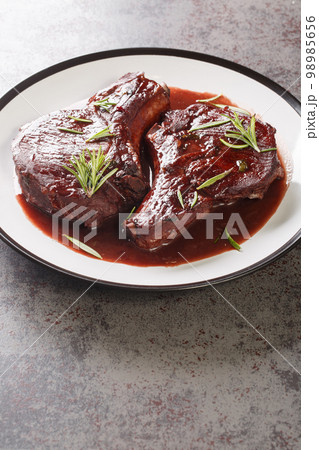Pan Seared Pork Chops with red wine sauce and herbs closeup on the plate. Vertical 98985656