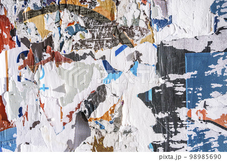 Torn paper collage background on an old poster on a street wall. Texture and surface of torn paper. 98985690