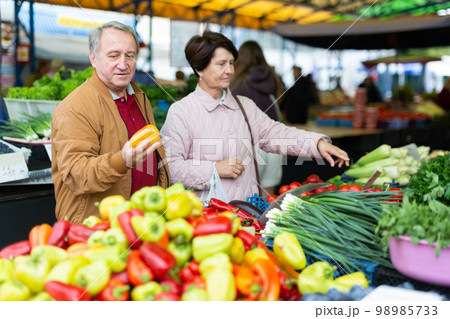 Aged man and woman customers buying pepper in open-air market 98985733