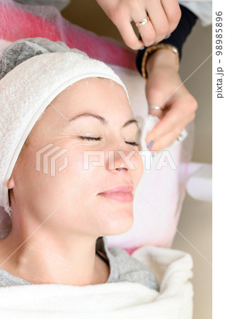 The cosmetologist wipes the remains of the mask with a napkin. 98985896