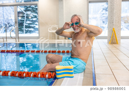 Senior swimmer in watersports goggles at the swimming pool Senior swimmer in watersports goggles at the swimming pool 98986001