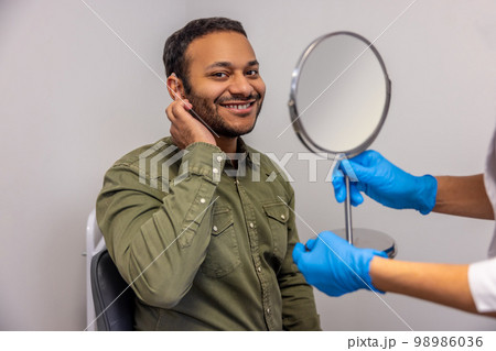 Doctor holding a mirror and showing the result to the patient Doctor holding a mirror and showing the result to the patient 98986036