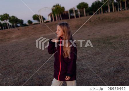Soft focus of little girl's hair while she is playing with someone actively on a field at sunset 98986442