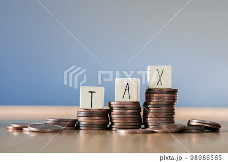 Wooden cubes with the word Tax on money climbing staits, pile of coins ,grow increasing tax rates,Tax Concept background closeup 98986565