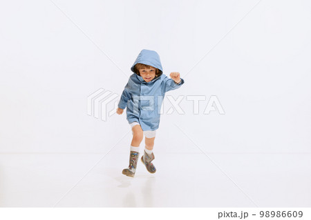 Spring walks. Happy little boy, kid wearing raincoat running isolated over white background. Concept of positive emotions, 50s, 60s vintage fashion style, childhood Spring walks. Happy little boy, kid wearing raincoat running isolated over white background. Concept of positive emotions, 50s, 60s vintage fashion style, childhood 98986609