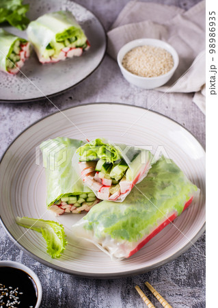 Fresh spring rolls with crab sticks, cucumber and lettuce. Vegetarian food. Vertical view 98986935