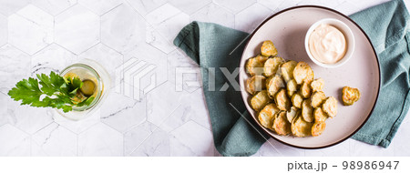 Fried pickles appetizer and sauce in a bowl on a plate. Homemade snack. Top view. Web banner 98986947