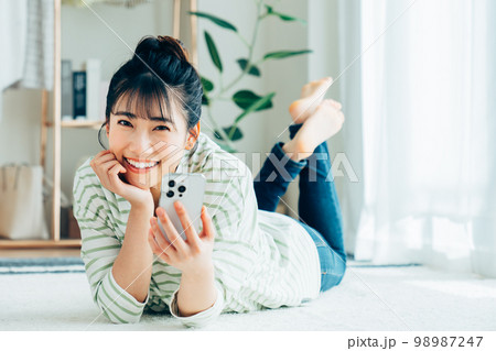 リビングでスマホを見る若い女性 リビングでスマホを見る若い女性 98987247