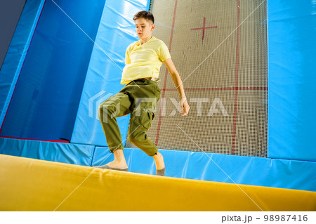 Teenage boy jumping on trampoline park in sport center Teenage boy jumping on trampoline park in sport center 98987416