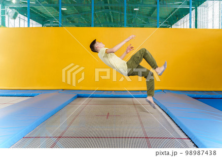 Teenage boy jumping on trampoline park in sport center  98987438