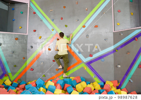 Teenage boy on climbing wall in trampoline center. Adventure and extreme for teenager concept 98987628