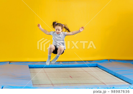 Happy little girl jumping on trampoline in fitness center 98987636