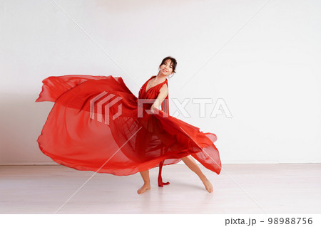 Dancer in a red flying dress. Woman ballerina dancing on a white studio background Dancer in a red flying dress. Woman ballerina dancing on a white studio background 98988756