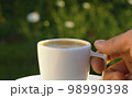 Male hand putting cup of coffee on a table 98990398