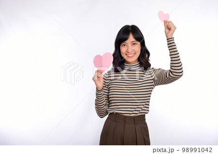 Beautiful young asian woman holding a paper heart while standing against white background. Beautiful young asian woman with paper heart. 98991042
