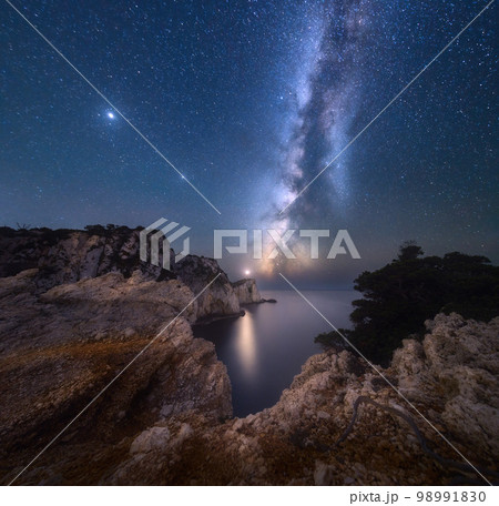 Milky Way and lighthouse on the mountain peak at starry night 98991830