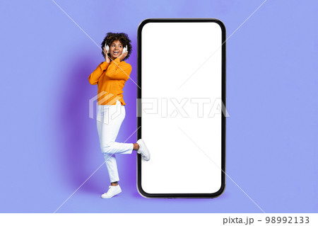 Pretty black lady listening to music in headphones, mobile app Pretty black lady listening to music in headphones, mobile app 98992133