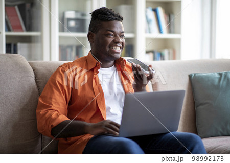 Young african american businessman working from home, sending voice mail 98992173