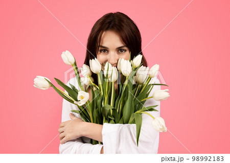 Cheerful young european lady smelling bouquet of flowers, enjoy lifestyle, aroma of tulips, rejoice spring 98992183