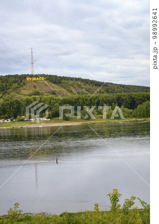 Tom River near the city of Kemerovo and fisherman crossing the river on foot Tom River near the city of Kemerovo and fisherman crossing the river on foot 98992641